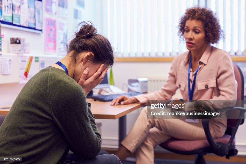 Female College Student Meeting With Campus Counselor Discussing Mental Health Issues