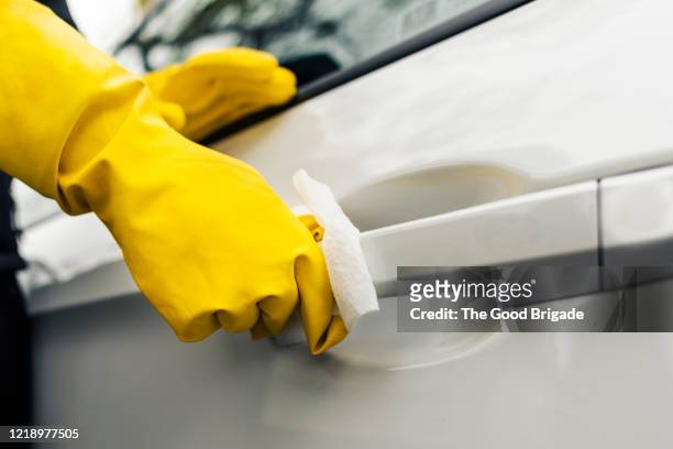 woman cleans exterior car door handle with disinfectant wipe - gul handske bildbanksfoton och bilder