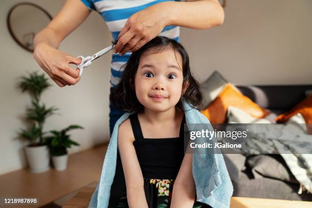 young girl pulling a face whilst getting a haircut at home - lockdown haircut stock pictures, royalty-free photos & images