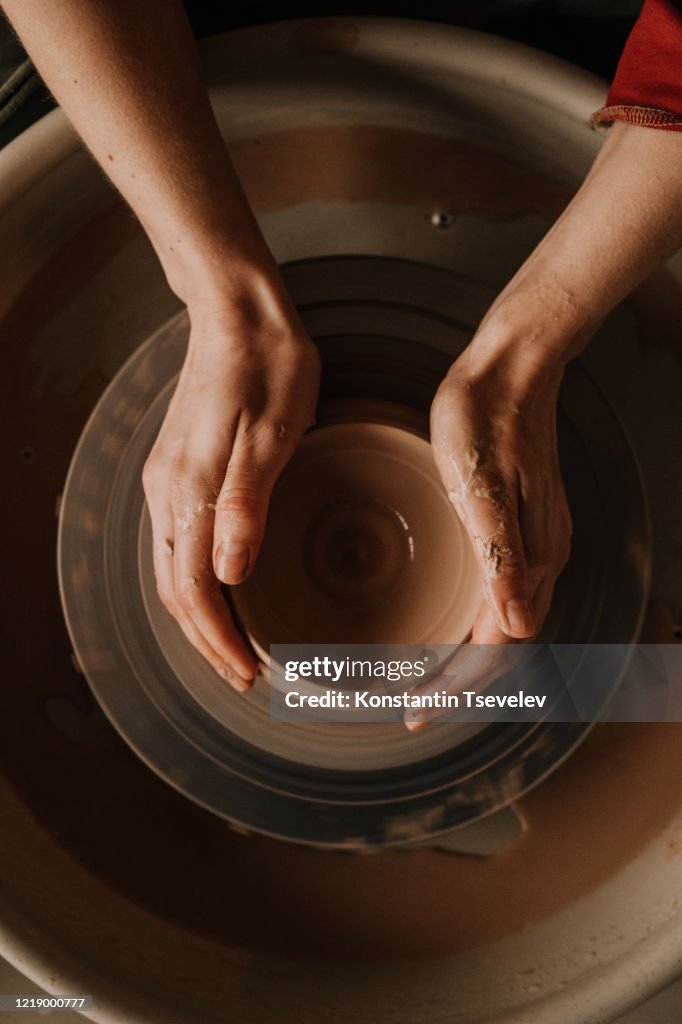 Woman making ceramic work with potter's wheel.