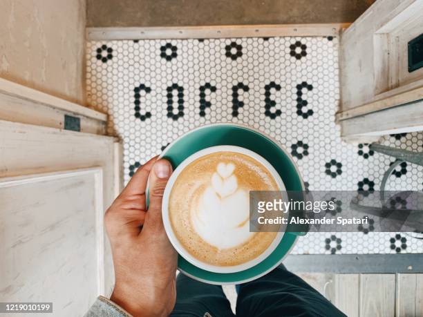 man holding a cup of coffee above "coffee" word on the floor - word cup ストックフォトと画像