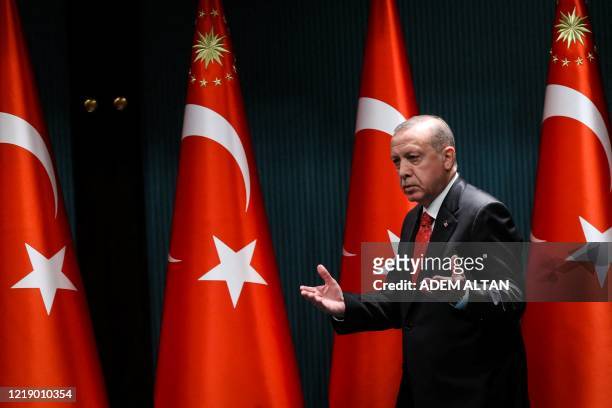 Turkish President Recep Tayyip Erdogan gestures and reacts as he arrives on stage to deliver a speech following a cabinet meeting, in Ankara, on June...