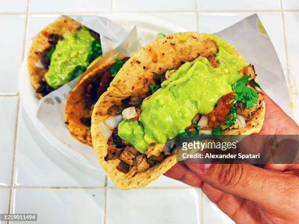man eating taco with chicken meat and guacamole, personal perspective - guacamole stock-fotos und bilder