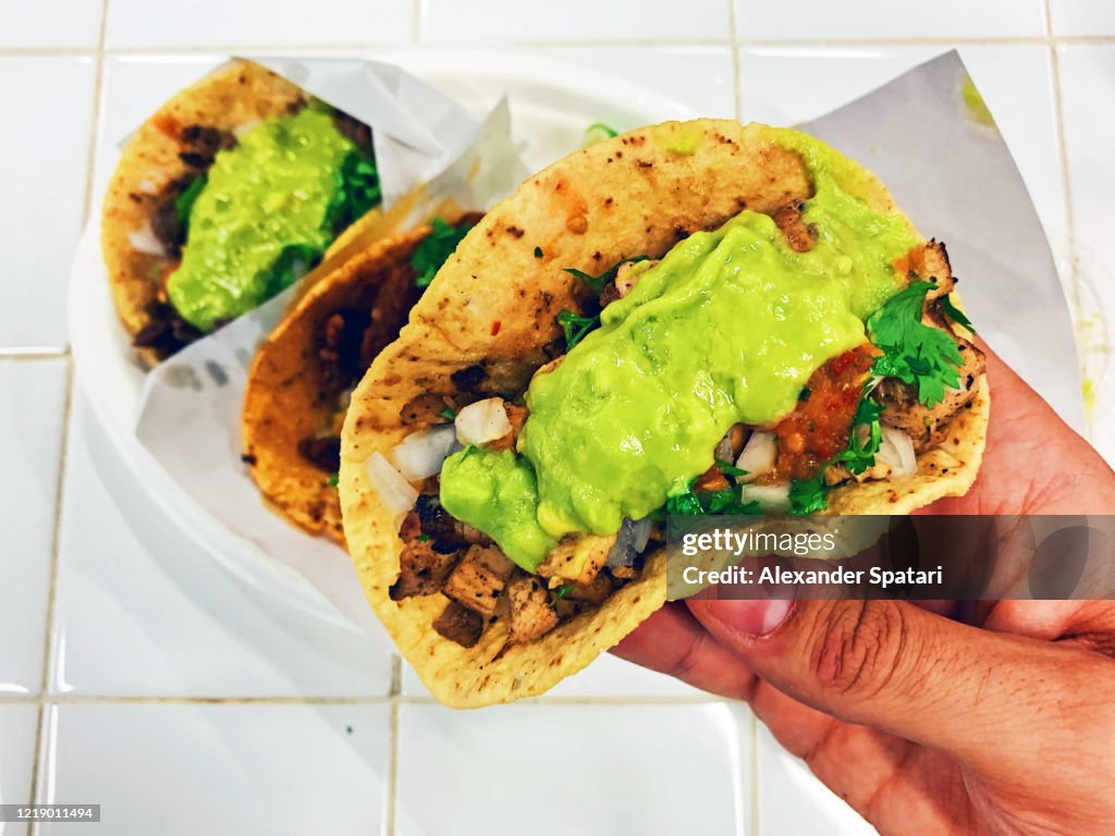 Man eating taco with chicken meat and guacamole, personal perspective