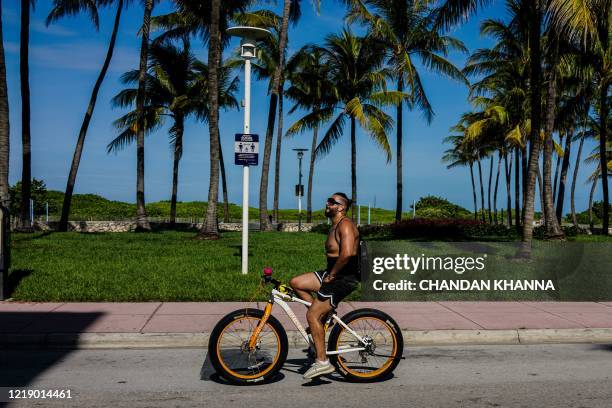 Man rides a bicycle on Ocean Drive in South Beach, Miami, on June 9, 2020. - Miami-Dade County beaches that were closed due to coronavirus pandemic...