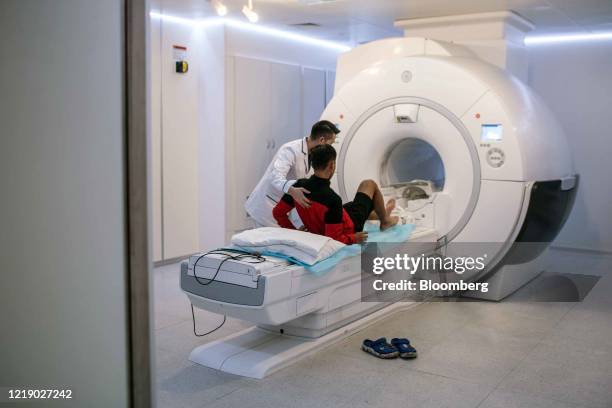 Medical technician assists a patient on a magnetic resonance imaging scanning machine at the Vinmec Times City International Hospital, operated by...