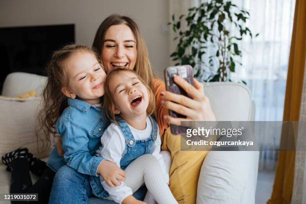 mãe alegre segurando smartphone fazendo selfie com as filhas - mother daughter webcam - fotografias e filmes do acervo