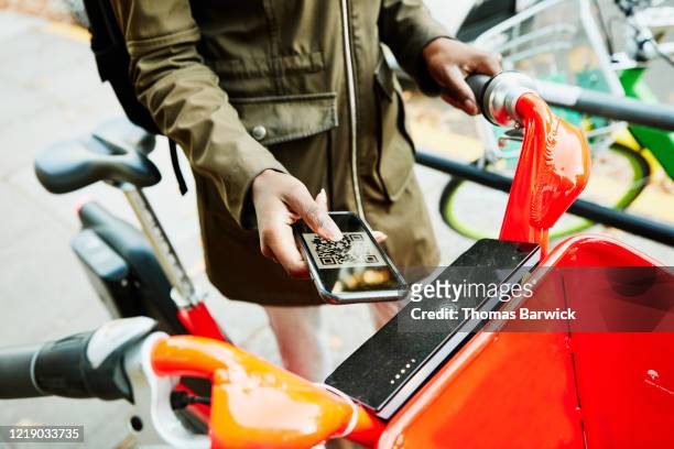 woman using qr code on smart phone to rent bike share bike - bike sharing stock-fotos und bilder