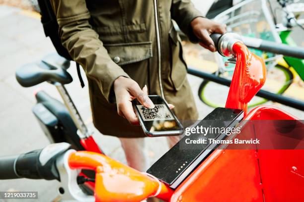 woman using qr code on smart phone to rent bike share bike - economía colaborativa fotografías e imágenes de stock