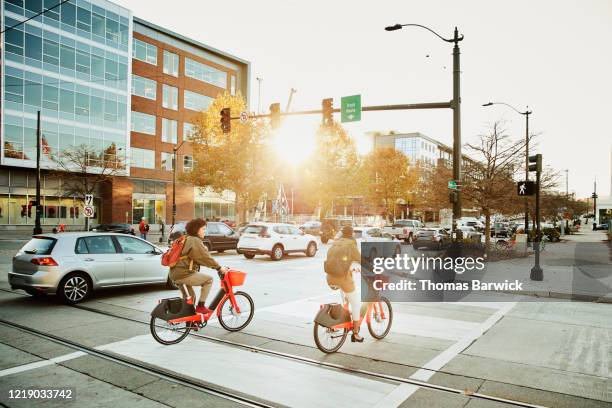 women commuting on electric bike share bikes during rush hour - economía colaborativa fotografías e imágenes de stock