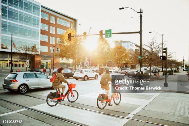women commuting on electric bike share bikes during rush hour - sharing economy stockfoto's en -beelden
