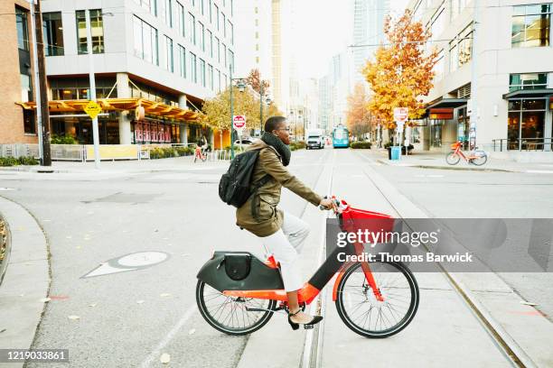 woman commuting to work on electric bike share bike - sustainable economy stock pictures, royalty-free photos & images