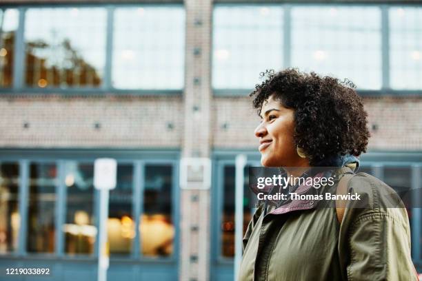 portrait of smiling woman on city street - groen jak stockfoto's en -beelden