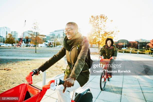 smiling woman commuting to work on electric bike share bike - city life authentic stock pictures, royalty-free photos & images