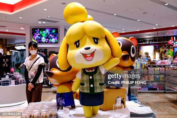 Customer walks past Animal Crossing video game characters at a Nintendo store in Tokyo on June 10, 2020.