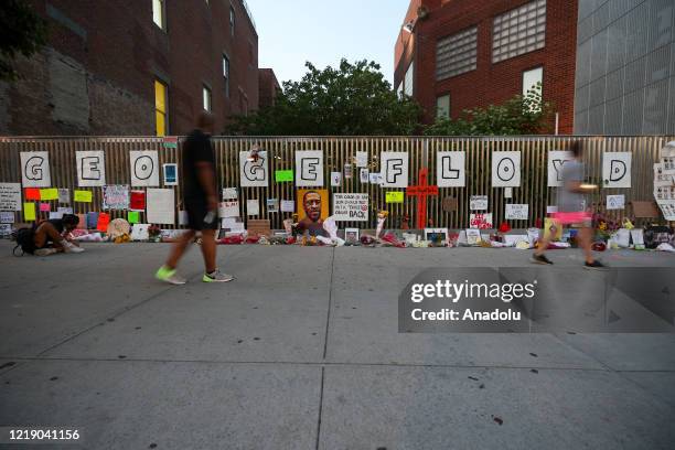 New Yorkers pay tribute to George Floyd by hanging his photo and his name written on papers on a wall and leaving flowers on his funeral day on the...