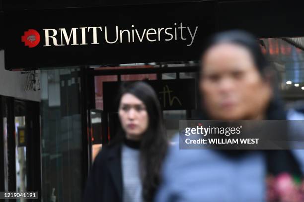 People walk past signage for an Australian university in Melbourne's central business district on June 10 as Australian officials and leading...