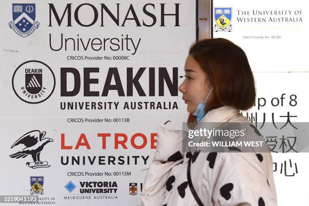 Woman walks past signage for Australian universities in Melbourne's central business district on June 10 as Australian officials and leading...