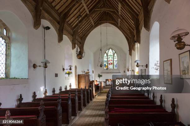 Looking east down the nave towards the altar and east window with historic wooden carved pews, fine wooden roof, whitewashed walls, interior of small...