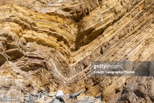 Strata of sandstone sedimentary rock in a coastal cliff with layers folded down to form a geological structure called a syncline, near Zambujeiro do...