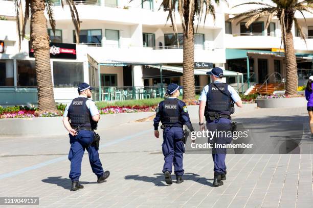 three police officers patrolling street in the city, corona virus pandemic restriction, background with copy space - nsw stock pictures, royalty-free photos & images