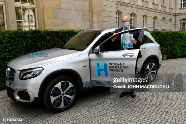 German Economy Minister Peter Altmaier wears a face mask as he poses next to a car to present the German government's hydrogen strategy, on June 10,...