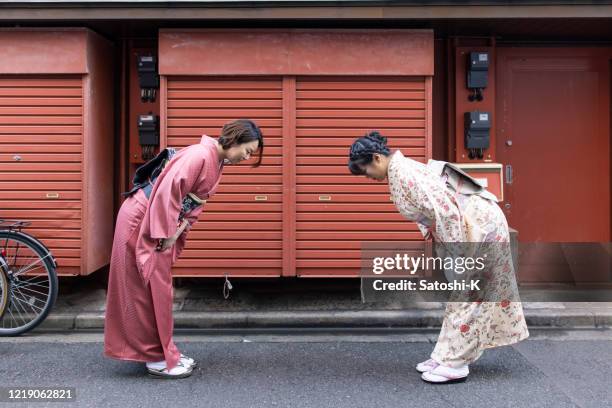 femmes japonaises dans le kimono s’inclinant sur la rue - saluer en s'inclinant photos et images de collection