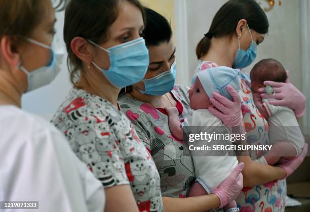 Nurses hold babies as foreign couples gather to collect them in the hotel Venice in the Ukrainian capital of Kiev on June 10, 2020. - Eight foreign...