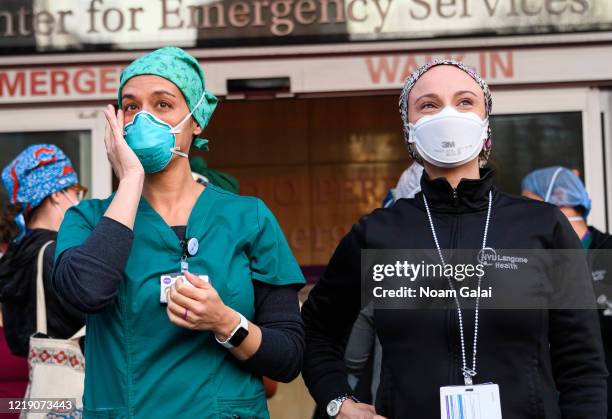 Medical workers stand outside NYU Langone Health hospital as people applaud to show their gratitude to medical staff and essential workers on the...