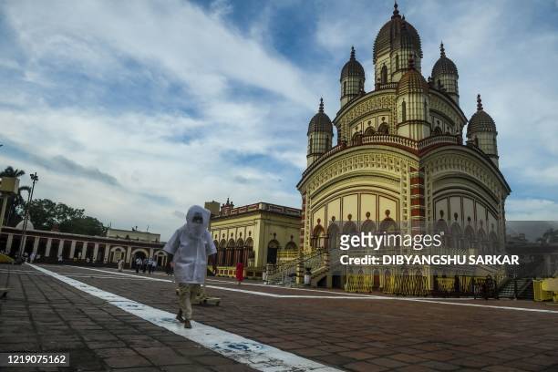 Hindu priest wearing protective gear walks on a white line in the premises of the Dakshineswar Kali Temple following the reopening of the places of...