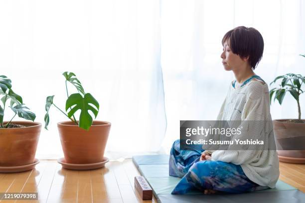 woman meditates in her living room at home - 胡坐　横 ストックフォトと画像