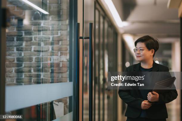 an asian chinese mid adult woman walking in the corridor in the office - business plan stock pictures, royalty-free photos & images