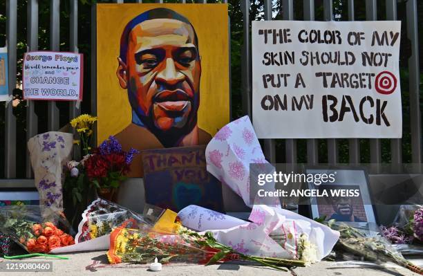 Flowers and painting adorn a tribute to George Floyd in Harlem on June 10 in New York City. - On May 25 Floyd, a 46-year-old black man suspected of...