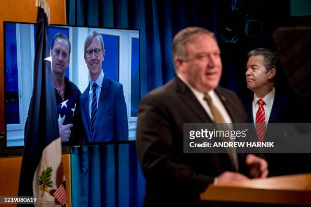 An image of Michael White, posing with US special envoy for Iran Brian Hook, released after being detained for two years in Iran, is displayed behind...