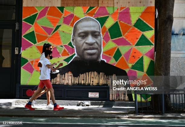 People walk past a boarded up store front with a George Floyd mural on June 10, 2020 in New York City. - On May 25 Floyd, a 46-year-old black man...