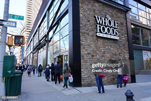 People are seen lined up in front of Whole Foods during the coronavirus pandemic on April 15, 2020 in New York City. Grocery stores across the...