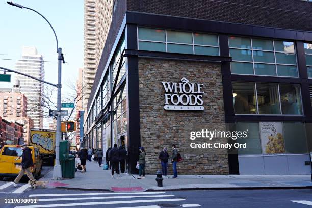 People are seen lined up in front of Whole Foods during the coronavirus pandemic on April 15, 2020 in New York City. Grocery stores across the...