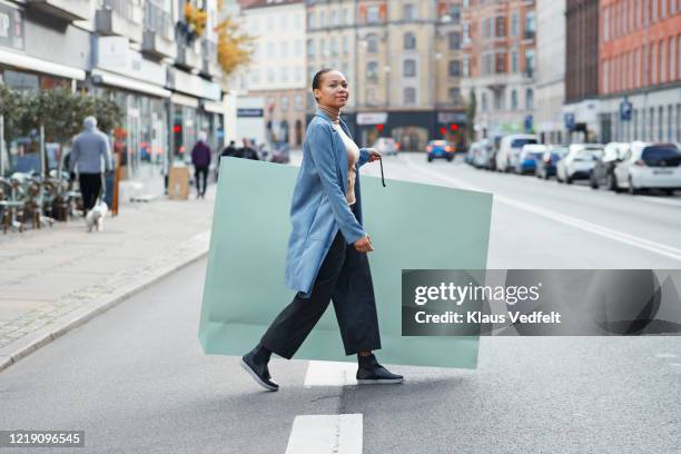 woman holding large shopping bag while walking on street - giant woman photos et images de collection