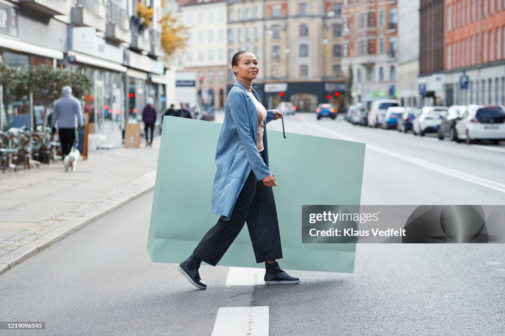 Woman holding large shopping bag while walking on street