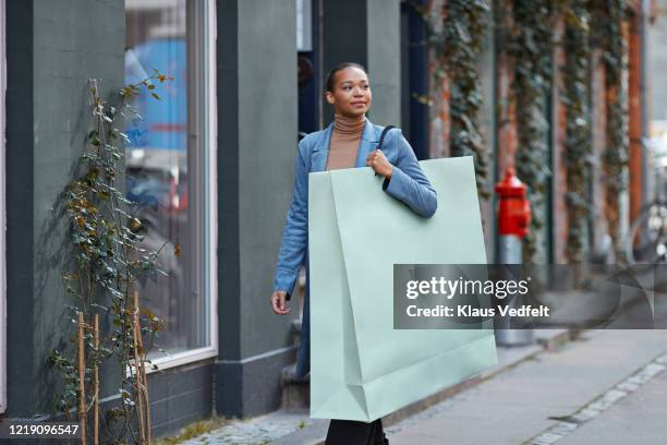 woman carrying large shopping bag on footpath - large purchase stock pictures, royalty-free photos & images