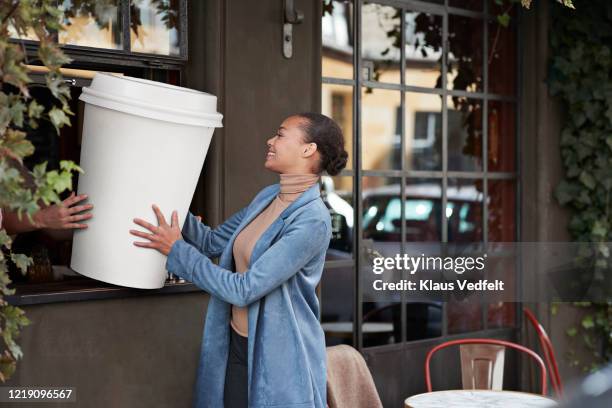 woman holding large disposable coffee cup at take away counter of cafe - 特大 個照片及圖片檔