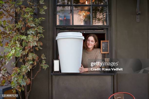 female barista holding disposable coffee cup at take out counter of cafe - women serving coffee stock-fotos und bilder