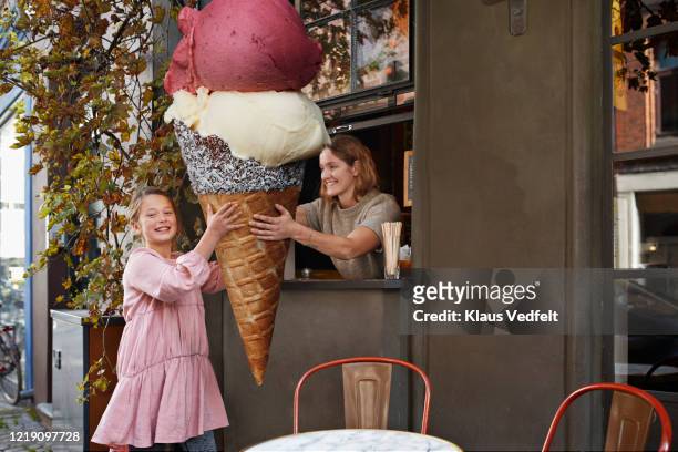 girl buying large ice cream cone from take out counter of cafe - temptation stock-fotos und bilder
