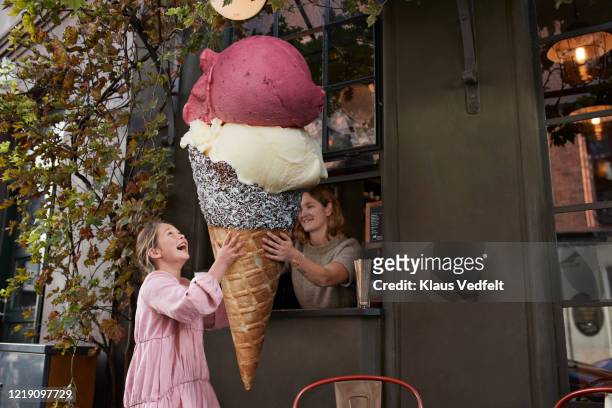 girl buying large ice cream cone from take out counter of cafe - ice cream counter stock-fotos und bilder