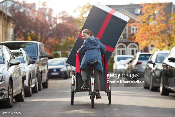 happy girl with large gift box on bicycle cart in city - handwagen stock-fotos und bilder