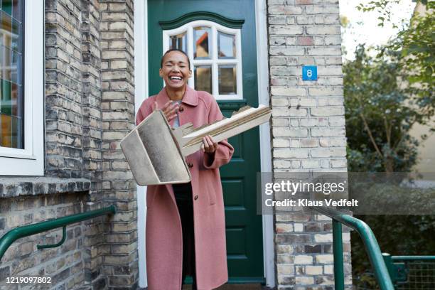 cheerful woman holding large key outside new house - home ownership keys stock pictures, royalty-free photos & images