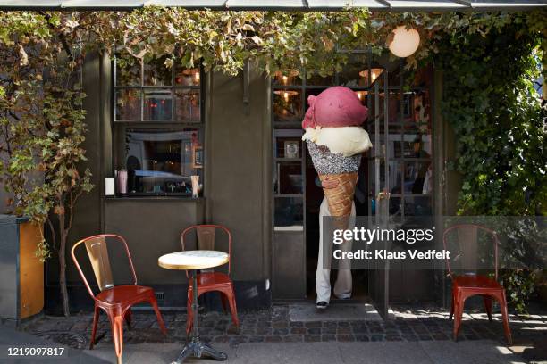 woman carrying large ice cream at sidewalk cafe - surdimensionné photos et images de collection