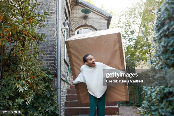 smiling woman carrying large package towards house - giant woman photos et images de collection