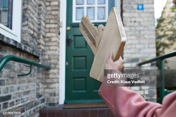 hand of woman holding large key outside house - new home pov stock pictures, royalty-free photos & images