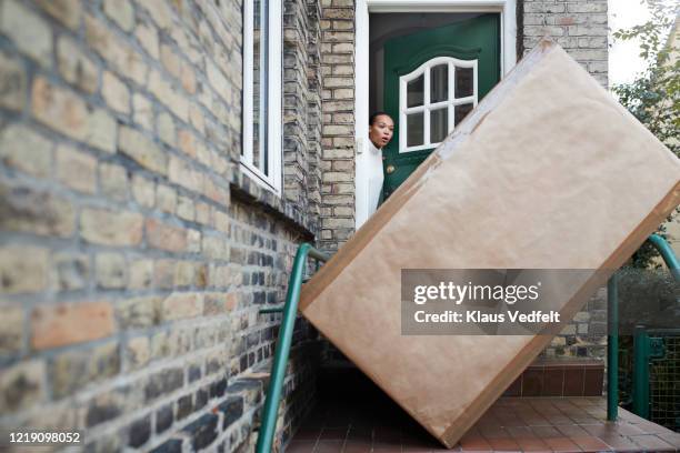 woman looking at package at entrance of house - big brown stock pictures, royalty-free photos & images